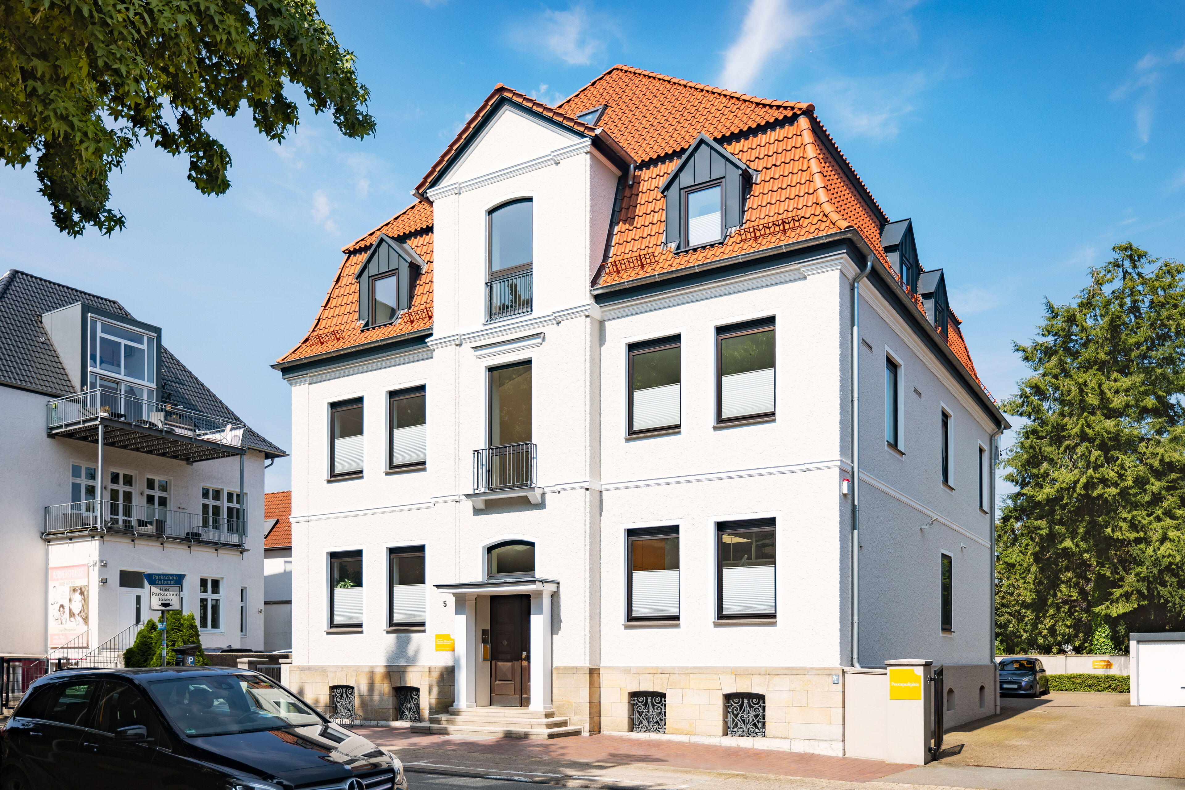 Außenansicht der Praxis Dr. Blümchen, Fachzahnarzt für Kieferorthopädie in Bielefeld, mit Parkmöglichkeiten für Autos und Fahrräder.