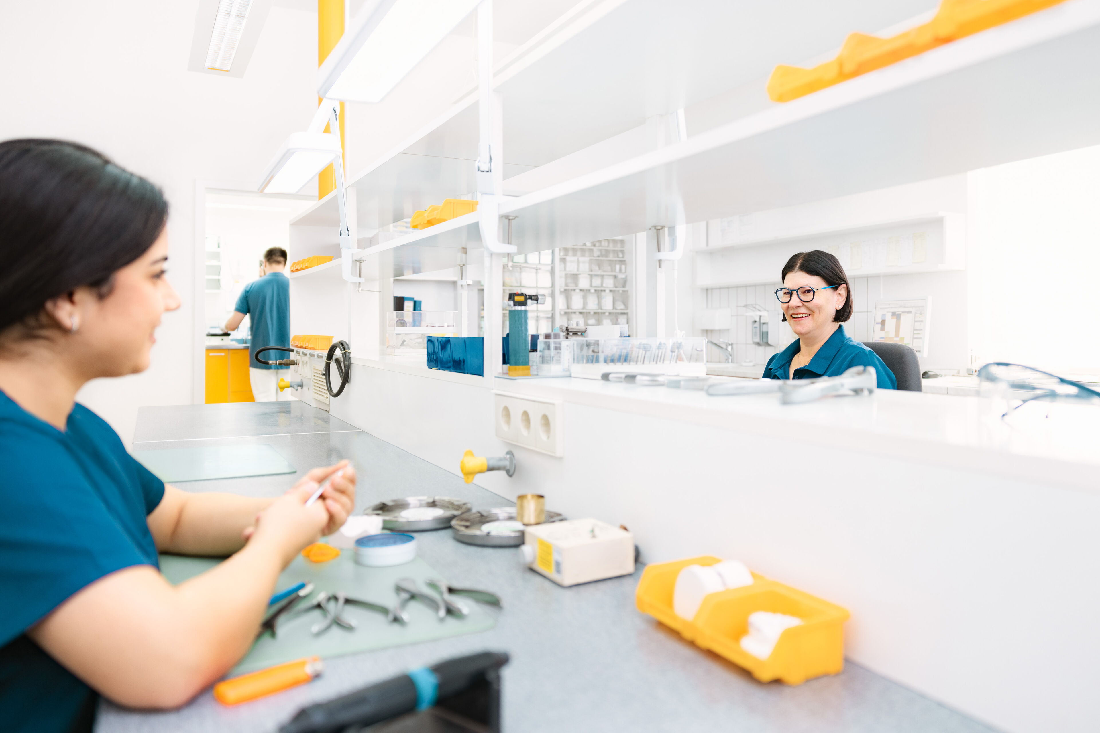 Zwei Mitarbeiterinnen im zahntechnischen Labor der kieferorthopädischen Praxis Dr. Blümchen in Bielefeld bei der Arbeit an kieferorthopädischen Geräten und Zahnspangen.