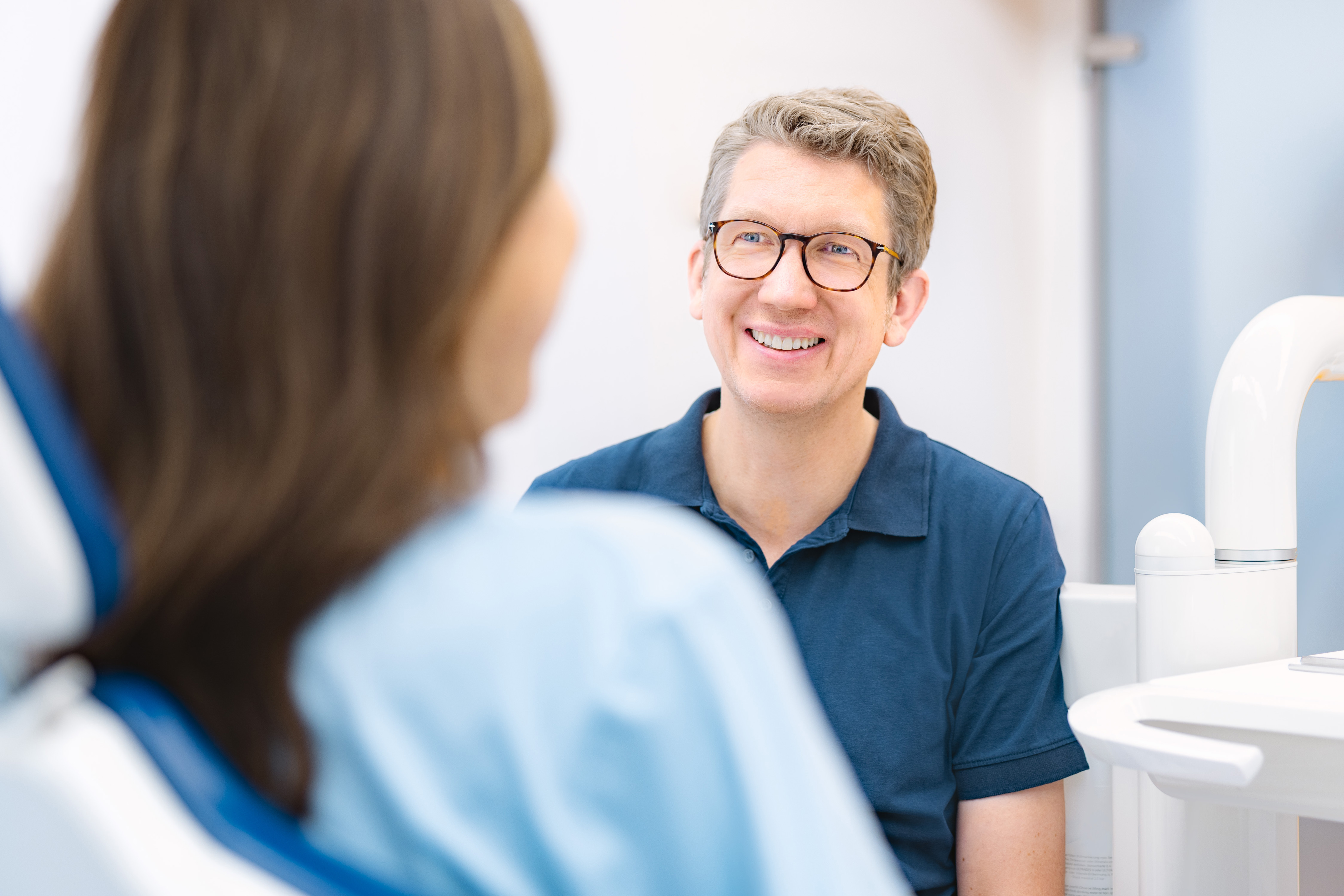 Dr. Torsten Blümchen, Fachzahnarzt für Kieferorthopädie in Bielefeld, im Gespräch mit einer Patientin während eines Termins in der Praxis.