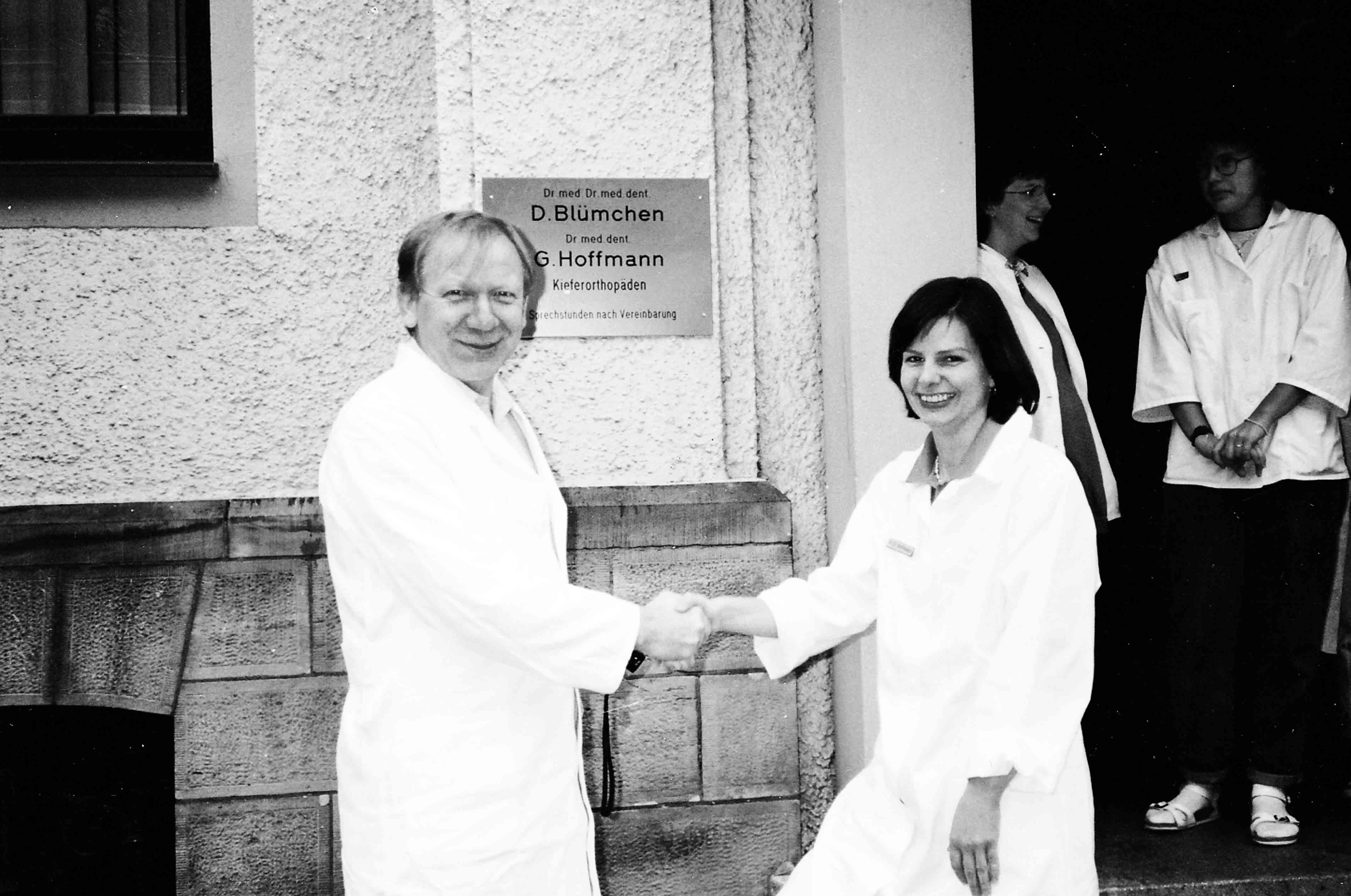 Dr. Dr. Dieter Blümchen mit seiner Kollegin Frau Dr. Hoffmann 1981 vor dem Eingansschild der Praxis Blümchen in Bielefeld, im Hintergrund zwei Arzthelferinnen.