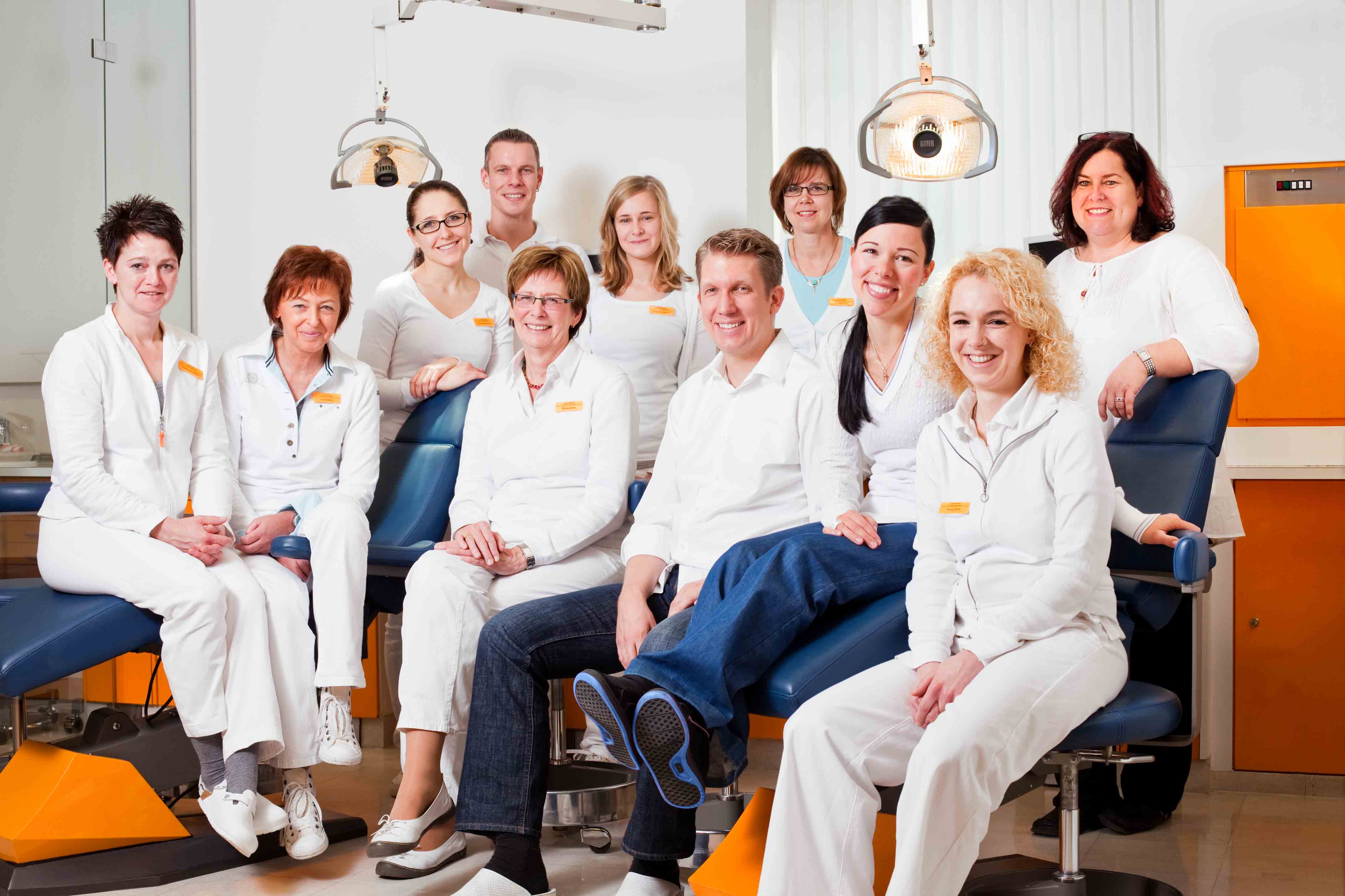 Das Team der Praxis Blümchen – Fachzahnarzt für Kieferorthopädie – in Bielefeld, Teambild von 2010. Die Gruppe steht und sitzt um einen Behandlungsstuhl in der Praxis.